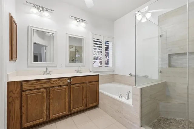 a bathroom with a bathtub a double vanity sink and mirror