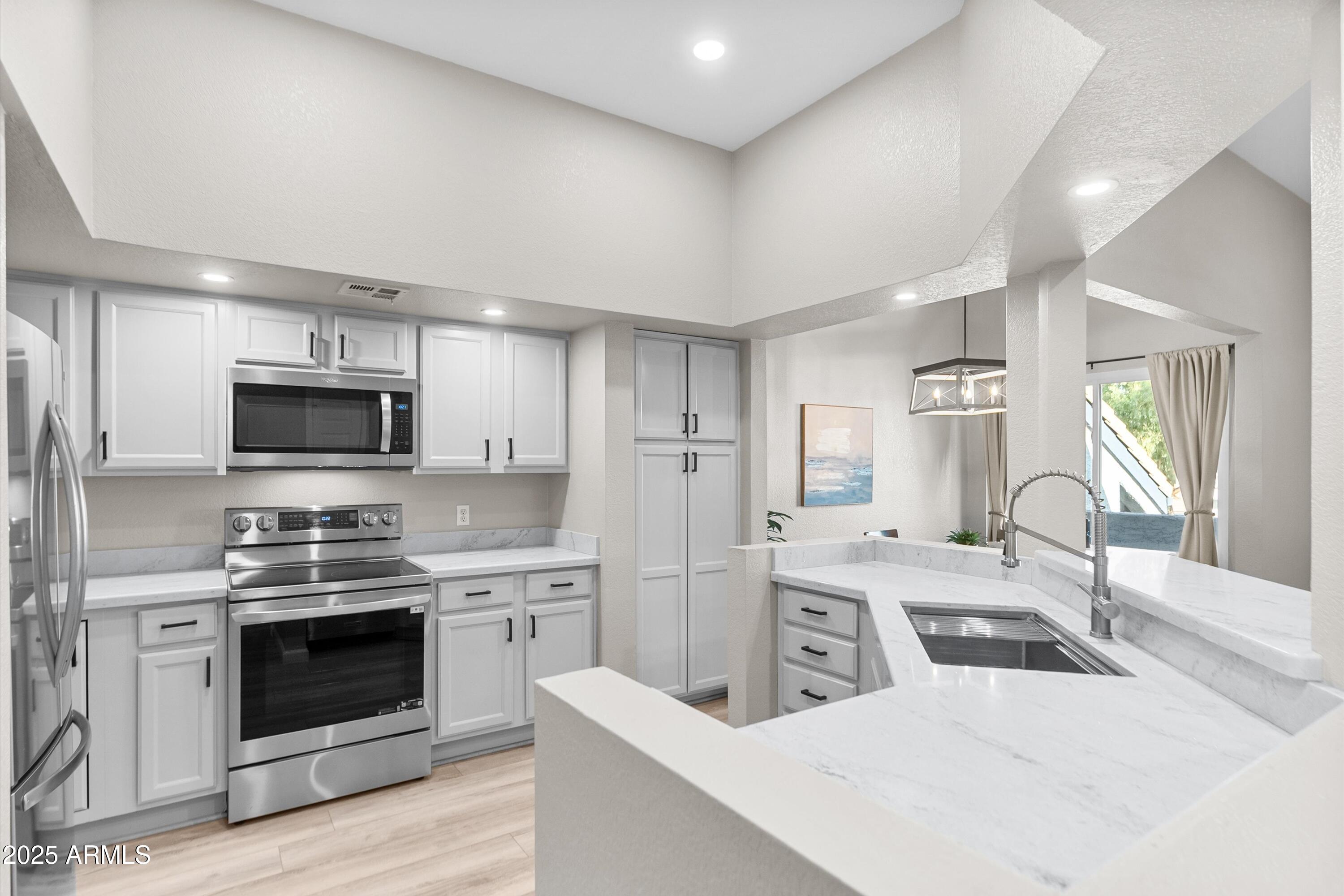 1331 West Baseline Road, Unit 338 Mesa, AZ 85202 - Photo 8 of 28 a kitchen with stainless steel appliances kitchen island granite countertop a stove sink and refrigerator