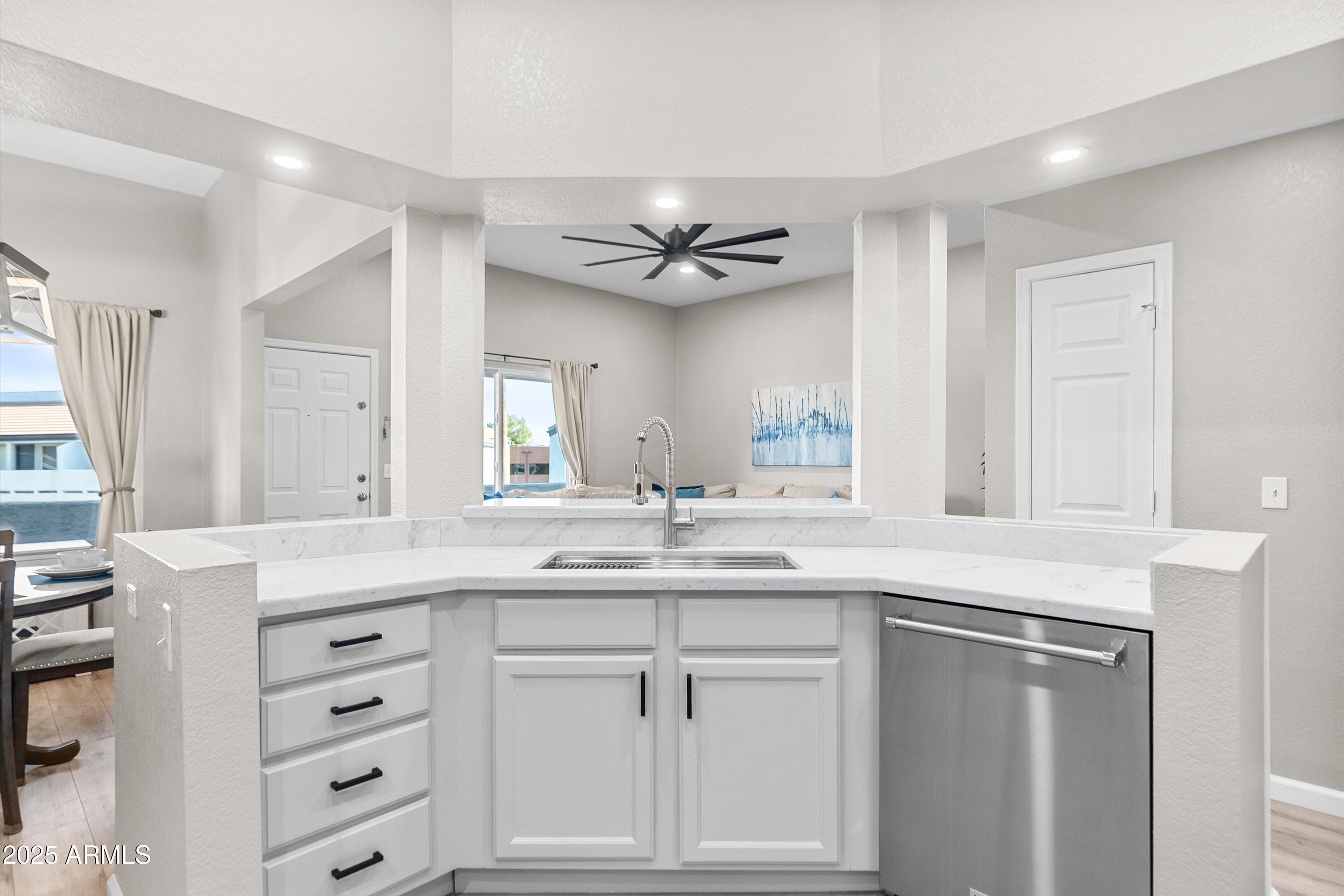1331 West Baseline Road, Unit 338 Mesa, AZ 85202 - Photo 9 of 28 a kitchen with a sink dishwasher a stove and white cabinets with wooden floor