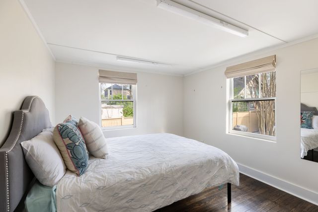 a view of a white house next to a yard with big trees