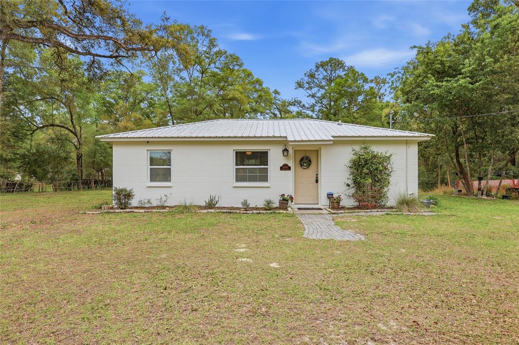 a view of a house with a yard and a large tree