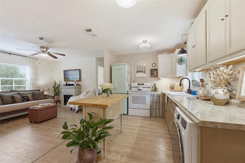 14285 Southwest 174th Street Archer, FL 32618 - Photo 9 of 25 a large white kitchen with stainless steel appliances granite countertop a couch a stove a sink dishwasher and white cabinets with wooden floor