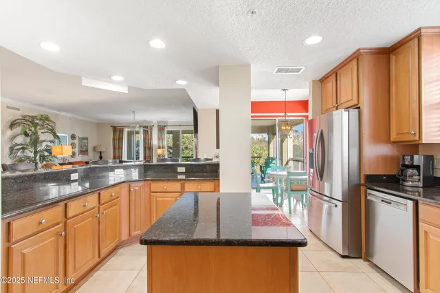 a kitchen with stainless steel appliances granite countertop a refrigerator a sink dishwasher a stove and white countertops with wooden floor