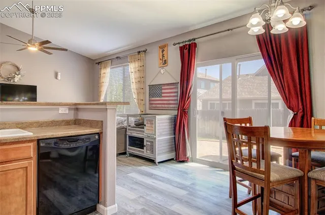 a open kitchen with stainless steel appliances granite countertop a stove top oven a refrigerator a dining table and chairs with wooden floor