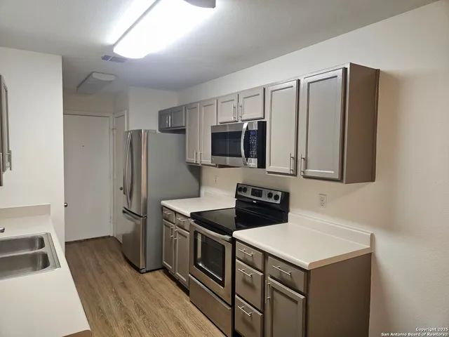 a kitchen that has a sink wooden cabinets and stainless steel appliances