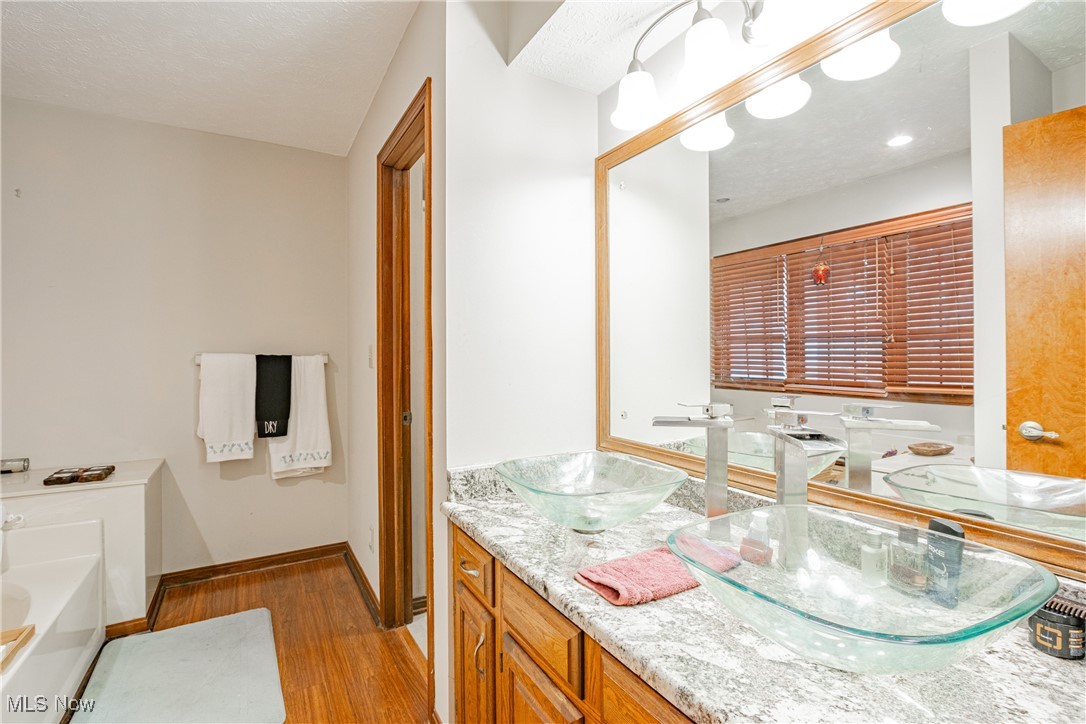 6743 Cedar Ridge Trail Clinton, OH 44216 - Photo 30 of 42 Bathroom featuring vanity, a bath, and hardwood / wood-style flooring