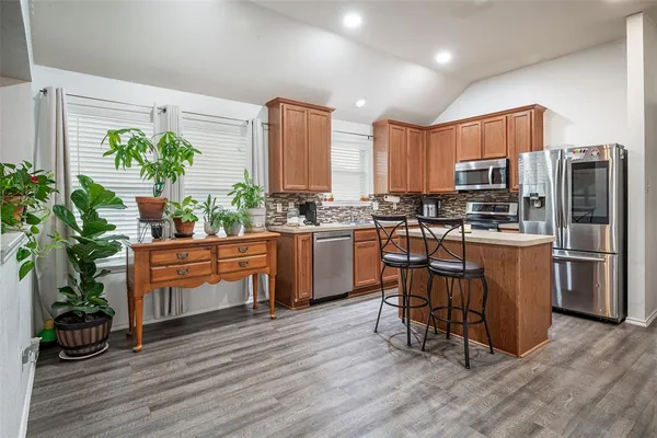 a kitchen with stainless steel appliances a table chairs refrigerator and wooden floor