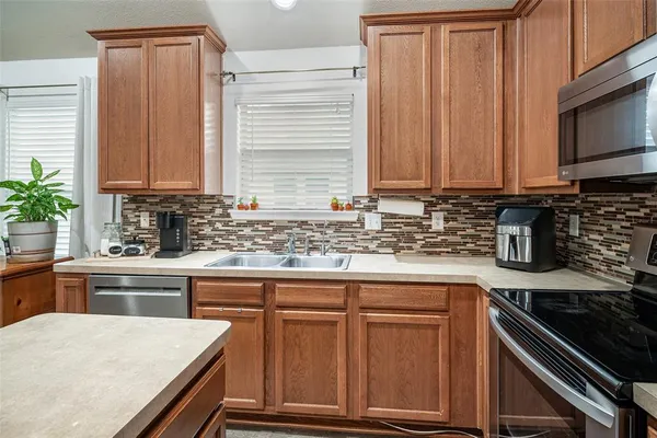 a kitchen with granite countertop wooden cabinets a stove top oven and potted plant