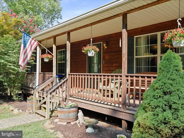a view of a house with a wooden deck and a bench