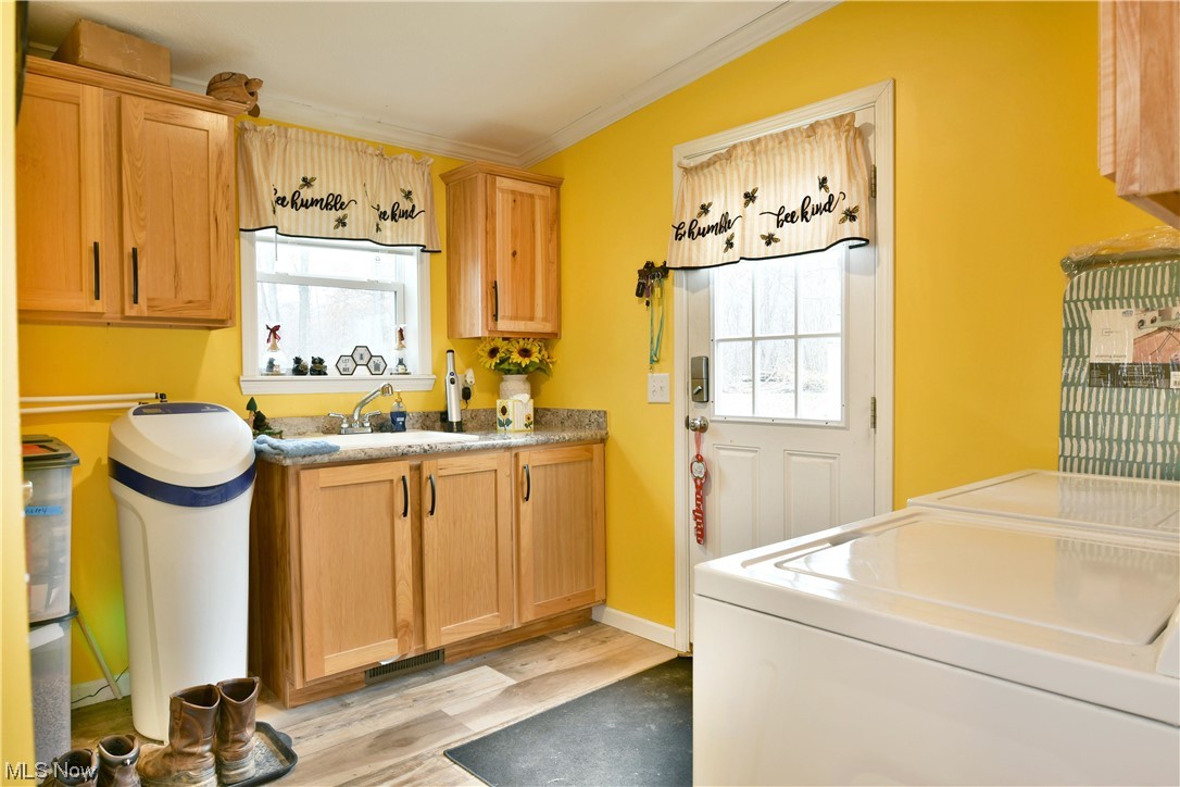 Side entry way featuring washing machine and clothes dryer, light wood-type flooring, light stone counters, and plenty of natural light