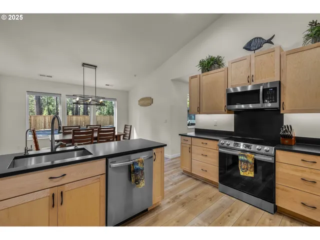 a kitchen with stainless steel appliances granite countertop a sink a stove and a wooden floors