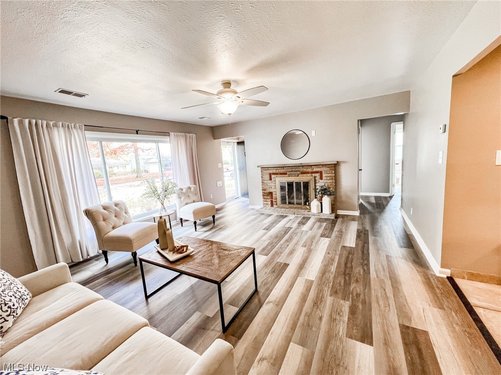 6830 Oakwood Road Parma Heights, OH 44130 - Photo 2 of 22 Living room featuring light wood-type flooring, a fireplace, a textured ceiling, and ceiling fan