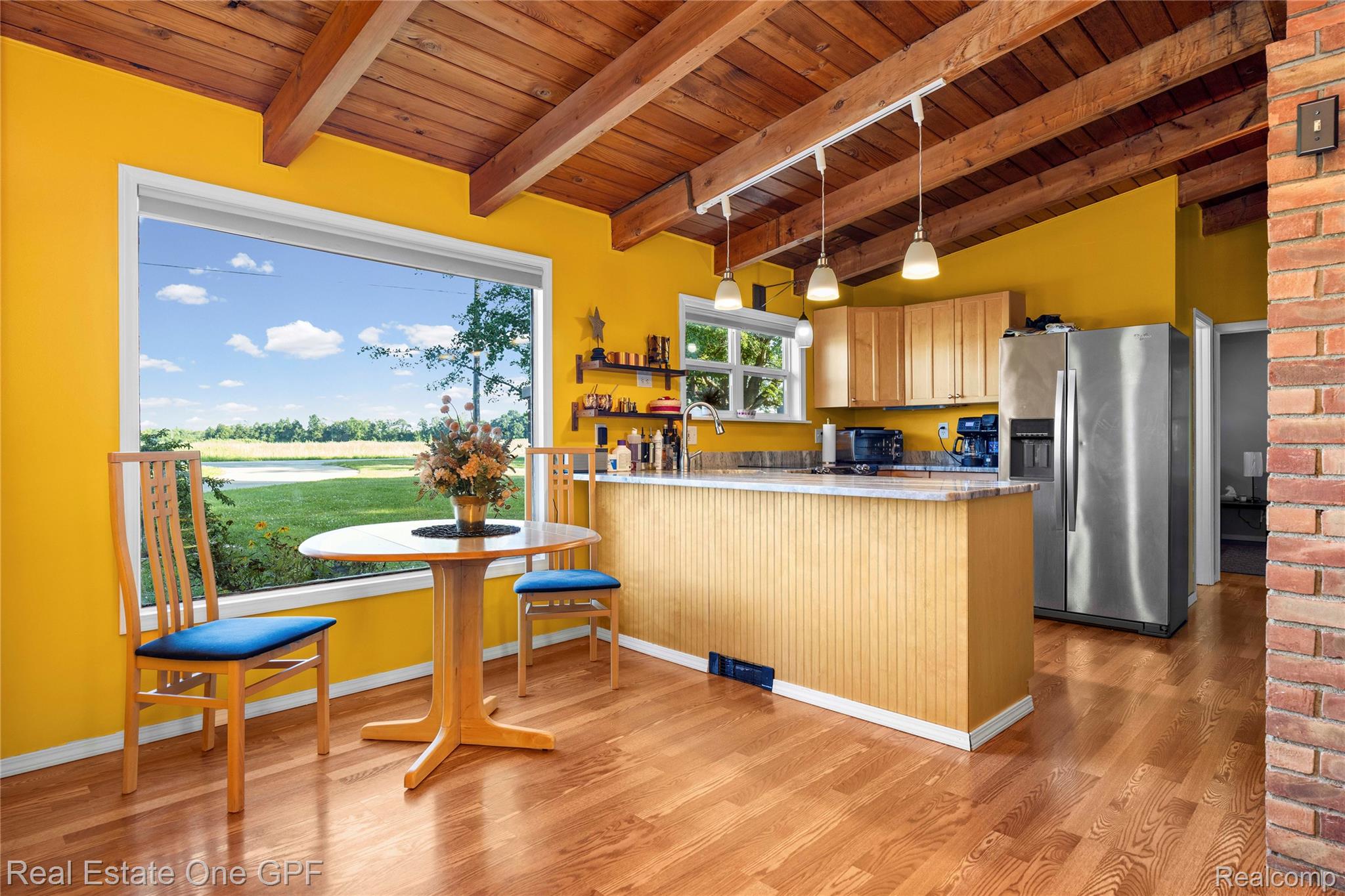 5068 Atkins Road North Street, MI 48049 - Photo 4 of 78 Exposed wood beam ceiling, hardwood flooring, large picture window with outdoor scenery, kitchen island with beadboard paneling, and pendant lighting
