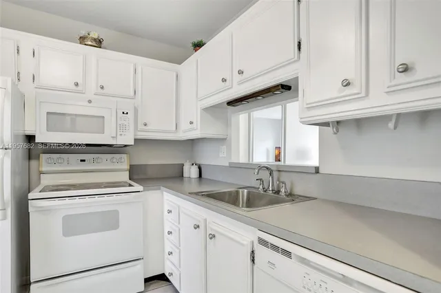 a kitchen with white cabinets and white appliances