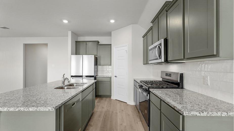 424 Epiphany Lane Lavon, TX 75166 - Photo 5 of 27 Spacious kitchen featuring an expansive island with dual sinks, gray cabinetry, light-colored granite countertops, stainless steel appliances, and wood-finish flooring