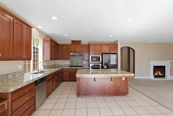 a kitchen with stainless steel appliances granite countertop sink stove top oven and cabinets