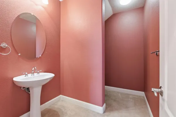 a view of a hallway with wooden floor and a bathroom