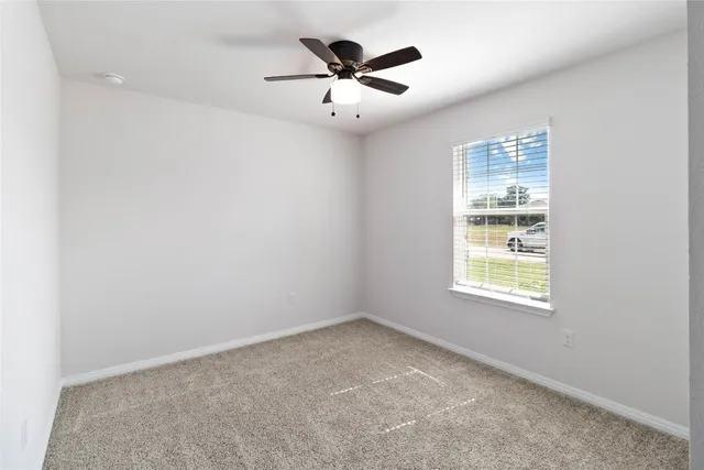 an empty room with window and ceiling fan