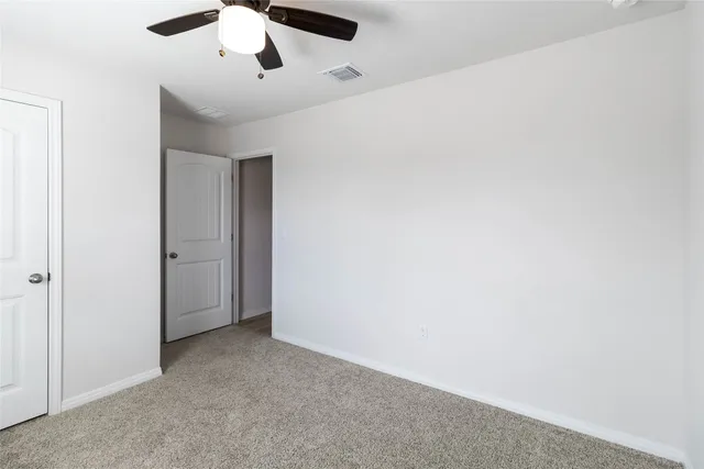 an empty room with a ceiling fan and carpet