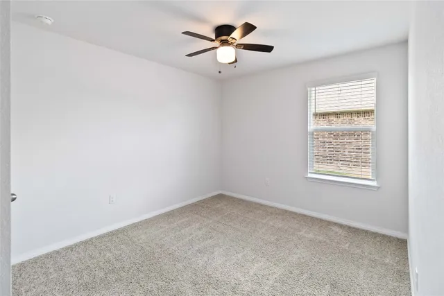 an empty room with a window and a ceiling fan