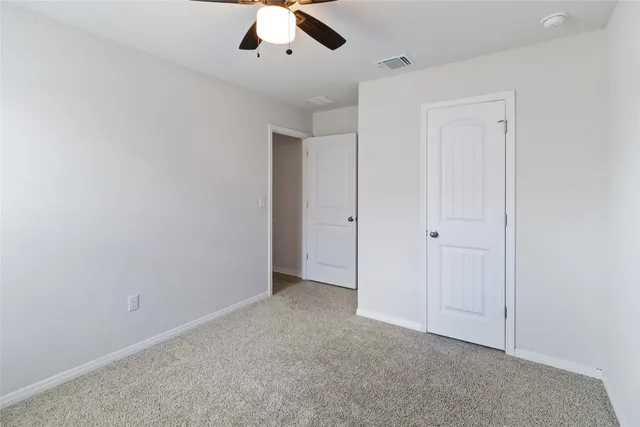 an empty room with a ceiling fan and carpet