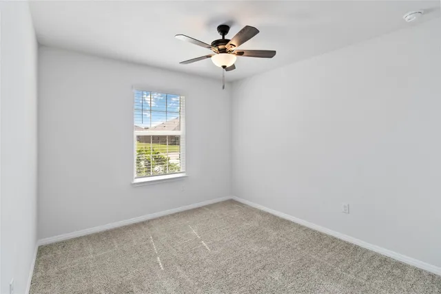 an empty room with a window and a ceiling fan