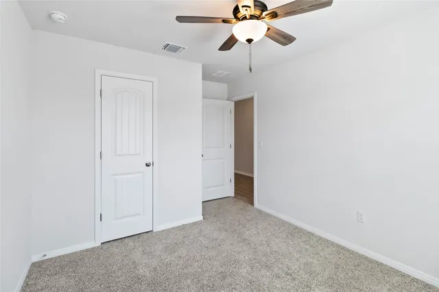 an empty room with a ceiling fan and a fan