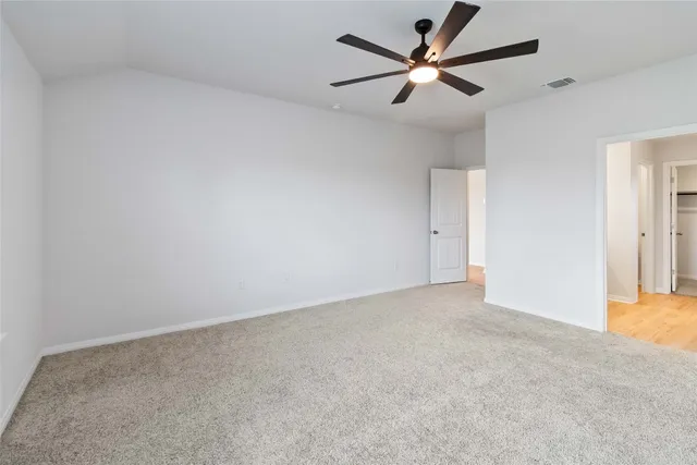 an empty room with closet and a ceiling fan