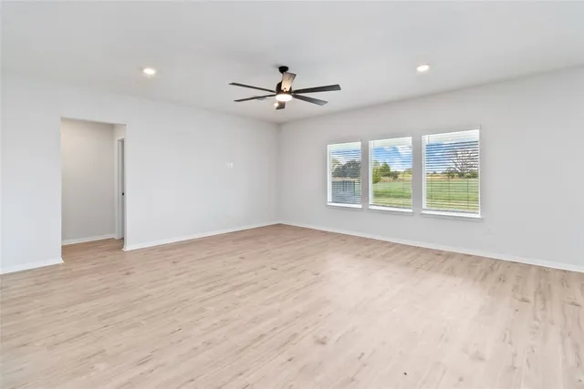 an empty room with windows and ceiling fan