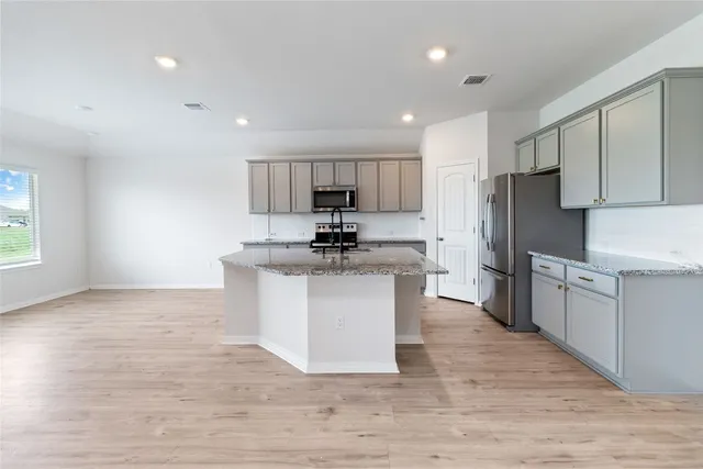 a kitchen with granite countertop a refrigerator stove top oven and cabinets