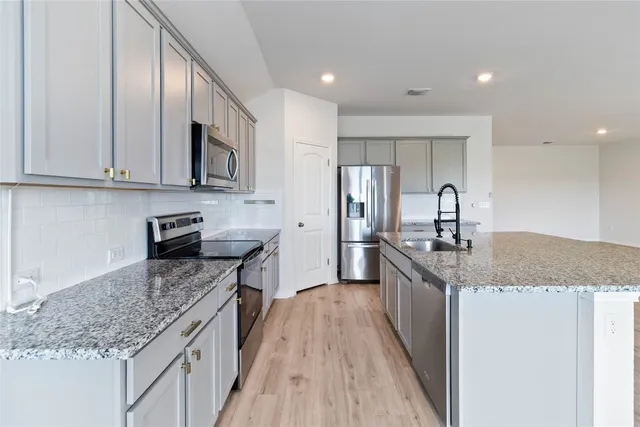 a kitchen with stainless steel appliances granite countertop a sink stove and refrigerator