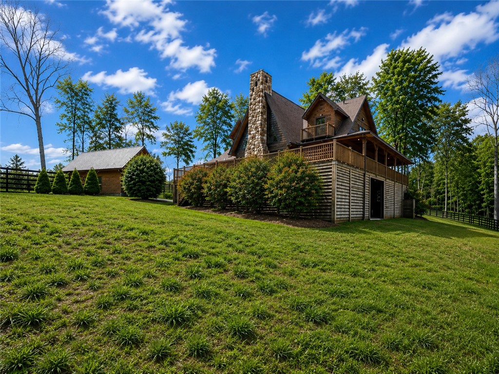 414 Devon Way Anderson, SC 29621 - Photo 35 of 50 Perched on a grassy hill, this log cabin with a stone chimney offers expansive outdoor living spaces and forest views.