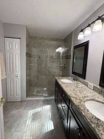 a bathroom with a granite countertop sink a large mirror and a shower