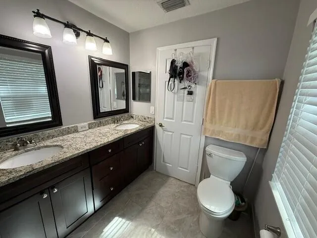 a bathroom with a granite countertop toilet sink and mirror