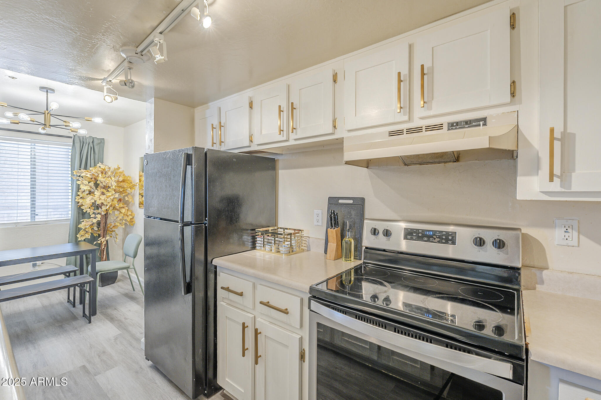 12123 West Bell Road, Unit 260 Surprise, AZ 85378 - Photo 12 of 29 a kitchen with stainless steel appliances a refrigerator a stove and white cabinets
