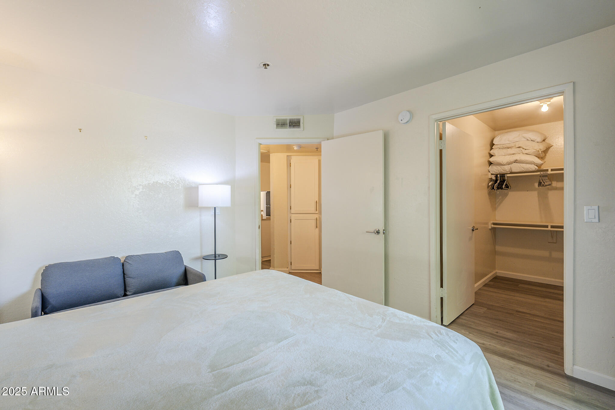 12123 West Bell Road, Unit 260 Surprise, AZ 85378 - Photo 15 of 29 a bedroom with a bed and closet with wooden floor