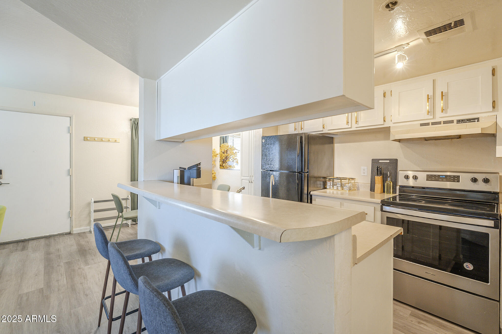 12123 West Bell Road, Unit 260 Surprise, AZ 85378 - Photo 9 of 29 a kitchen with stainless steel appliances kitchen island granite countertop a table chairs and a refrigerator