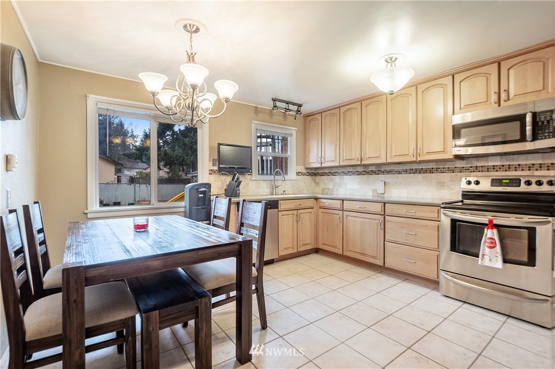 8216 Custer Road Southwest Lakewood, WA 98499 - Photo 8 of 20 a kitchen with stainless steel appliances granite countertop a stove a sink dishwasher a dining table and chairs with wooden floor