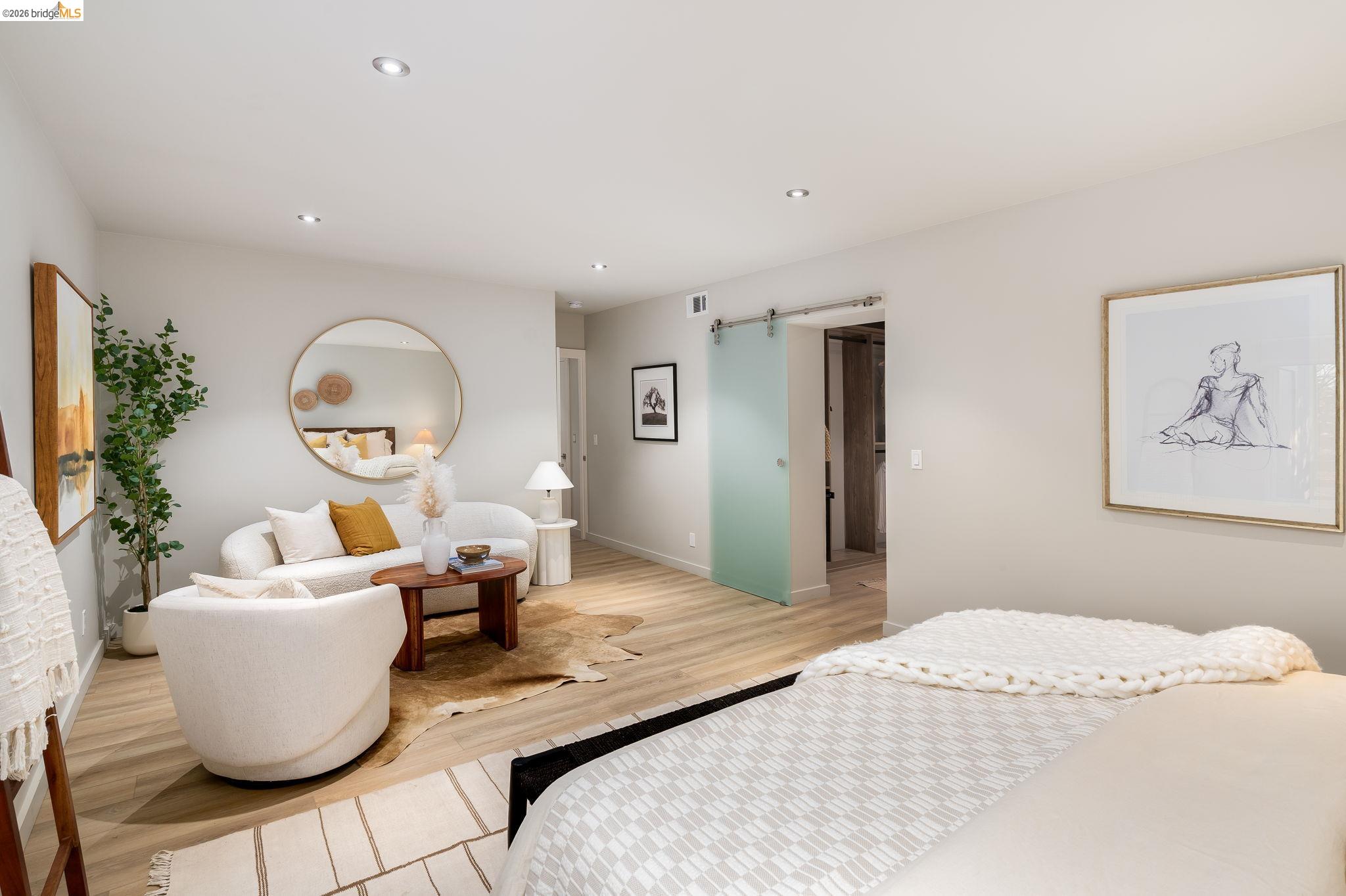 Bedroom with a barn door, wood finished floors, and recessed lighting