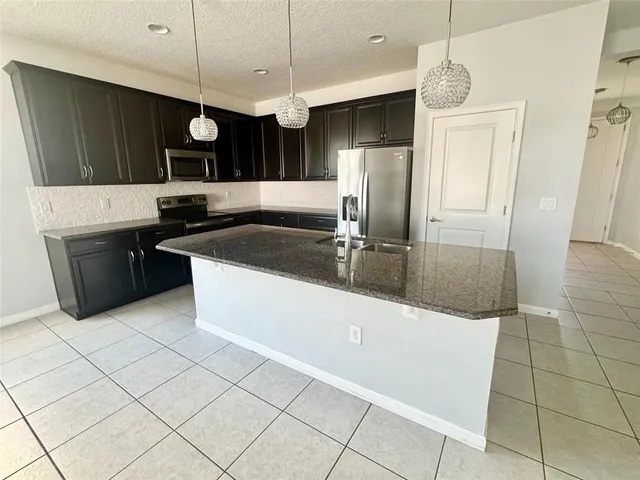 a kitchen with stainless steel appliances granite countertop a sink a stove and a refrigerator