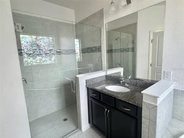a bathroom with a granite countertop sink a mirror and a shower