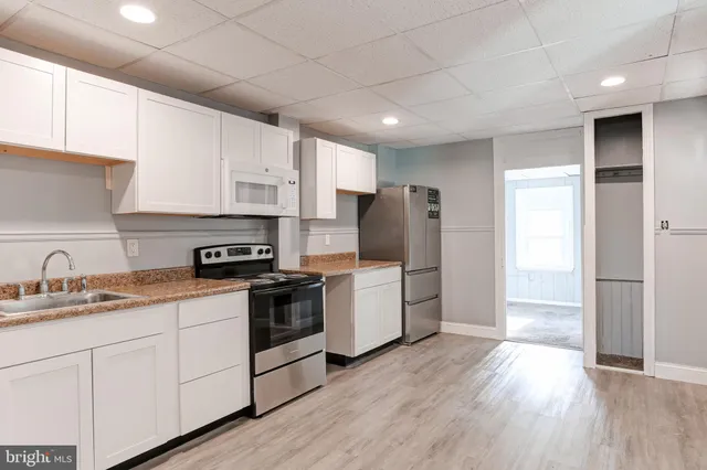 a kitchen with a refrigerator a sink dishwasher and a stove with wooden floor