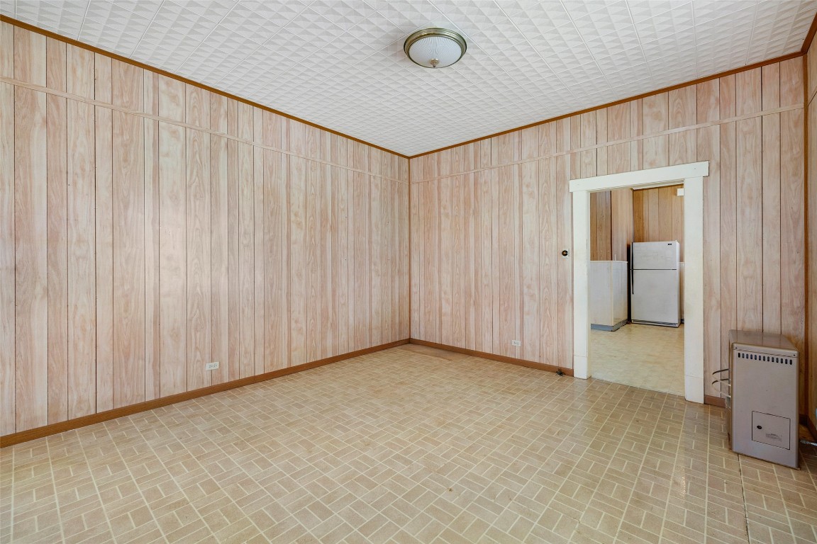 303 Vernon Street Taylor, TX 76574 - Photo 16 of 37 Spare room with brick patterned floor, heating unit, wooden walls, and baseboards