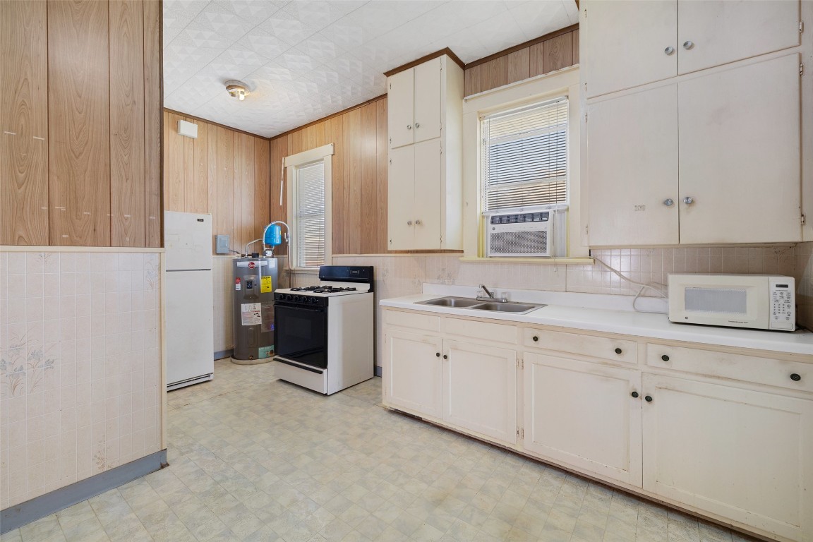 303 Vernon Street Taylor, TX 76574 - Photo 27 of 37 Kitchen featuring white appliances, wooden walls and sink