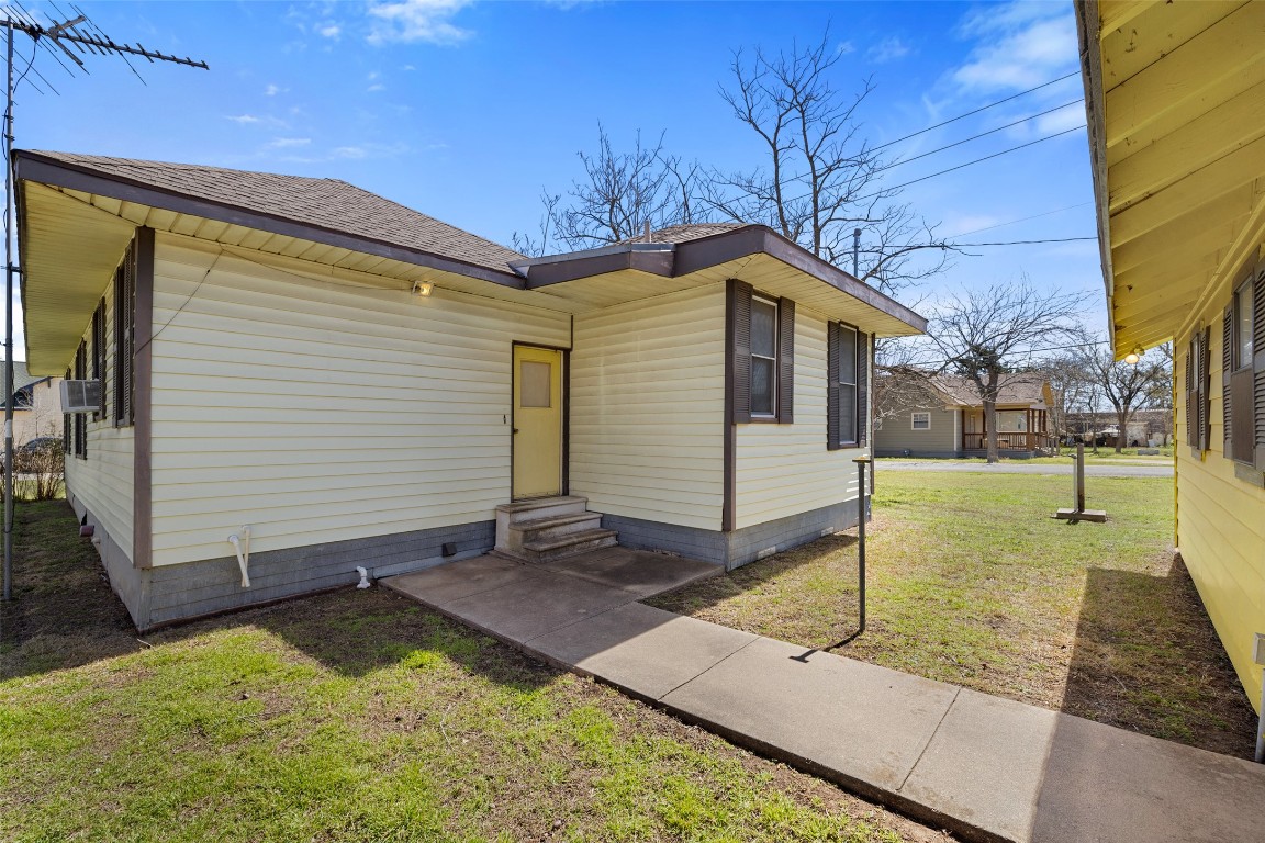 303 Vernon Street Taylor, TX 76574 - Photo 8 of 37 View of front facade featuring entry steps, roof with shingles, a front yard, and cooling unit