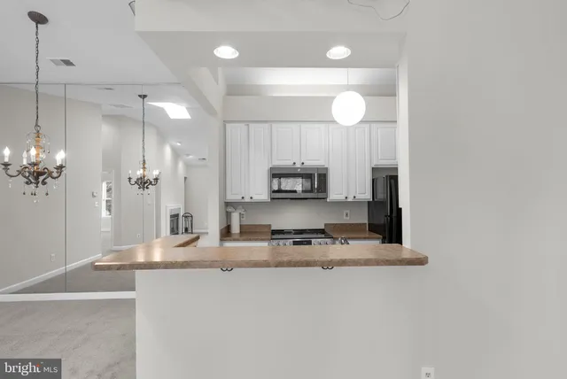 a kitchen with stainless steel appliances granite countertop white cabinets and a refrigerator