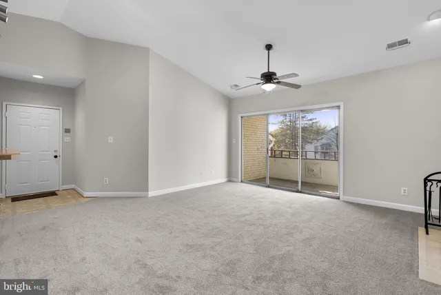 an empty room with a kitchen and chandelier fan