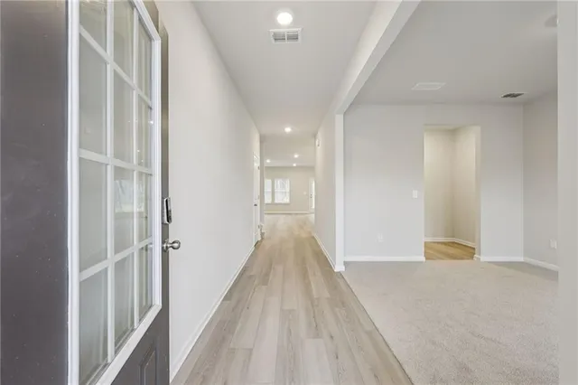 a view of a hallway with wooden floor and a bathroom