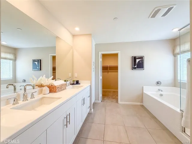 a bathroom with a double vanity sink toilet mirror and bathtub