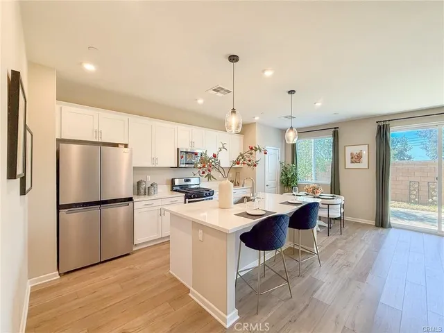 a kitchen with kitchen island a dining table chairs and a refrigerator